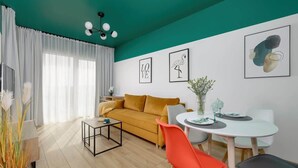 Uma sala de estar moderna com sofá, mesa de jantar, cadeiras e obras de arte nas paredes.