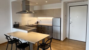Eine moderne Küche mit Esstisch und Stühlen, einem eingebauten Backofen und einem Kühlschrank.