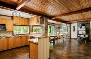 A spacious kitchen with wooden cabinets, a central island, and a dining area with chairs.
