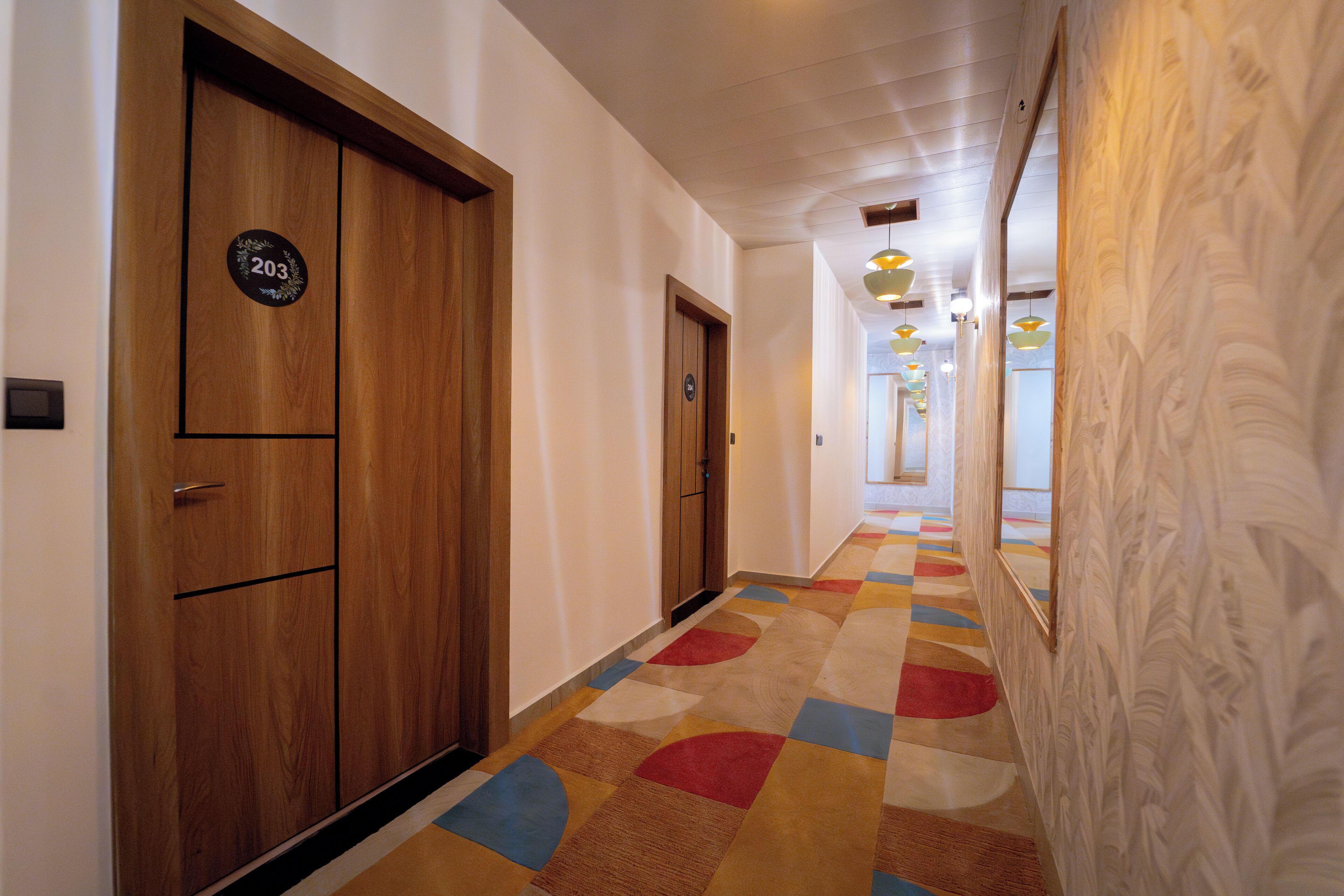 A hallway with wooden doors, a carpet with geometric patterns, and a patterned wall.