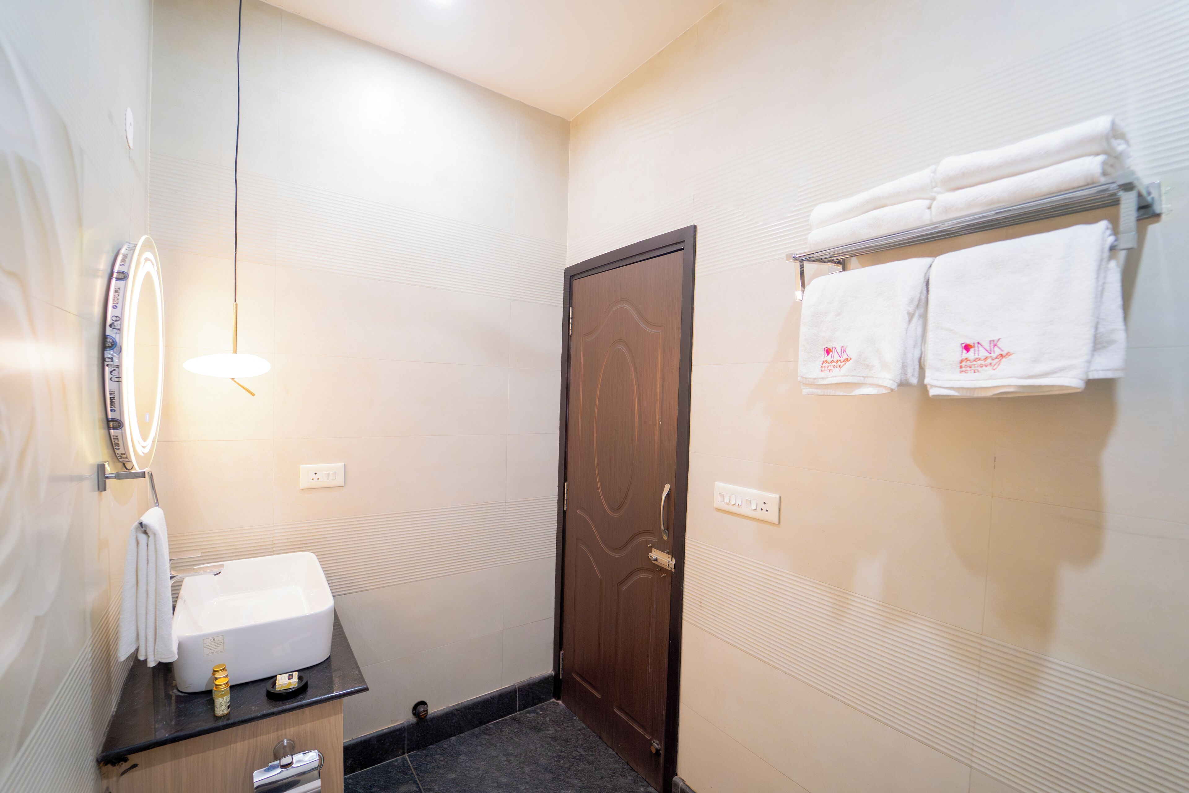 A bathroom with a sink, mirror, towel rack, and a door.