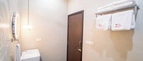 A bathroom with a sink, mirror, towel rack, and a door.