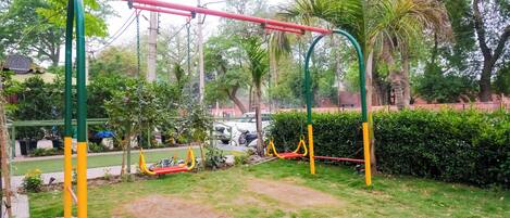 A playground with swings and a red and yellow slide.