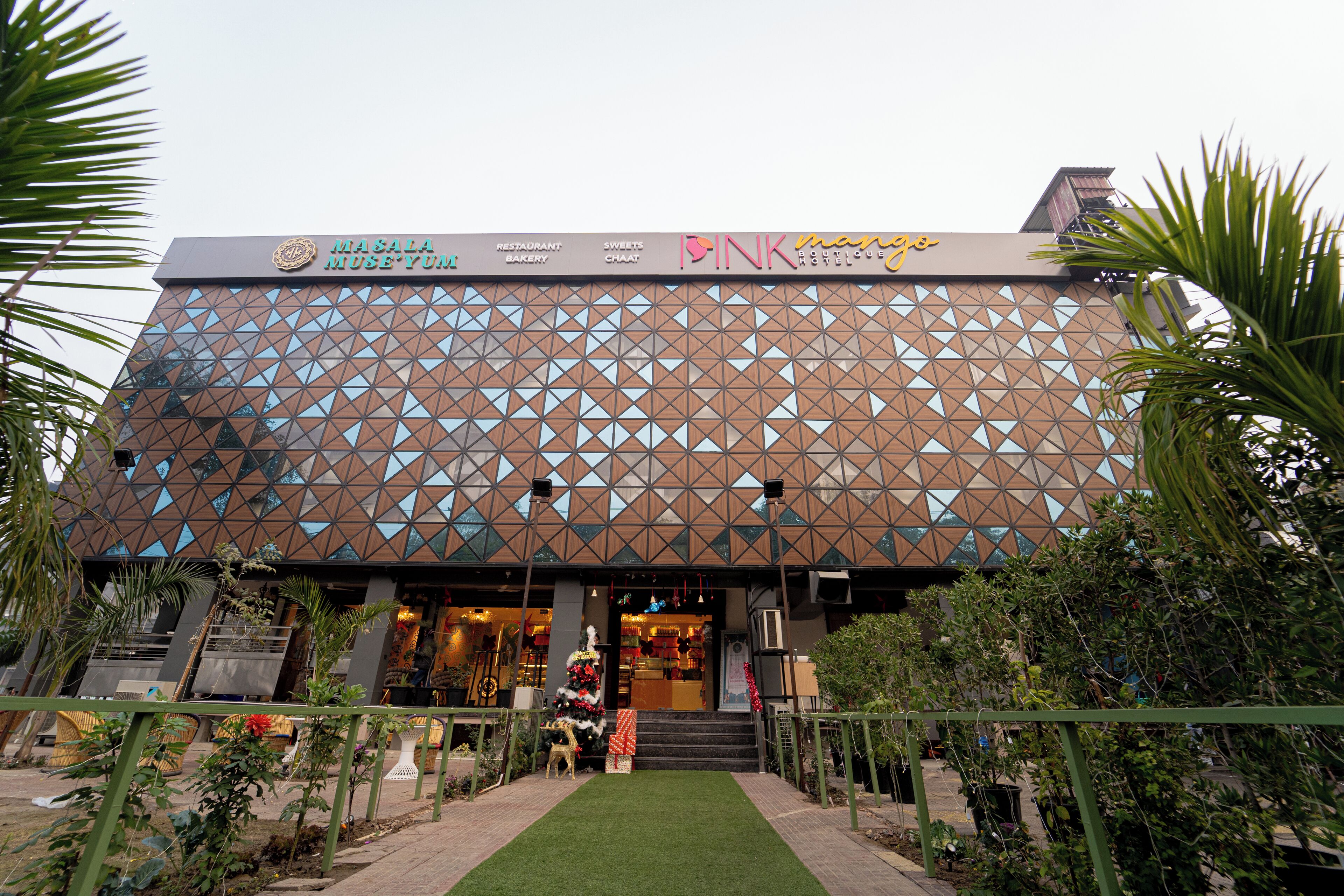 A building with a geometric facade, a staircase leading to the entrance, and a small Christmas tree.