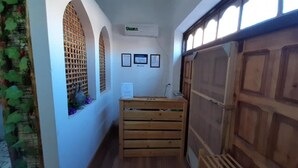 Un couloir étroit avec des bancs en bois, une porte en bois et un climatiseur fixé au mur.