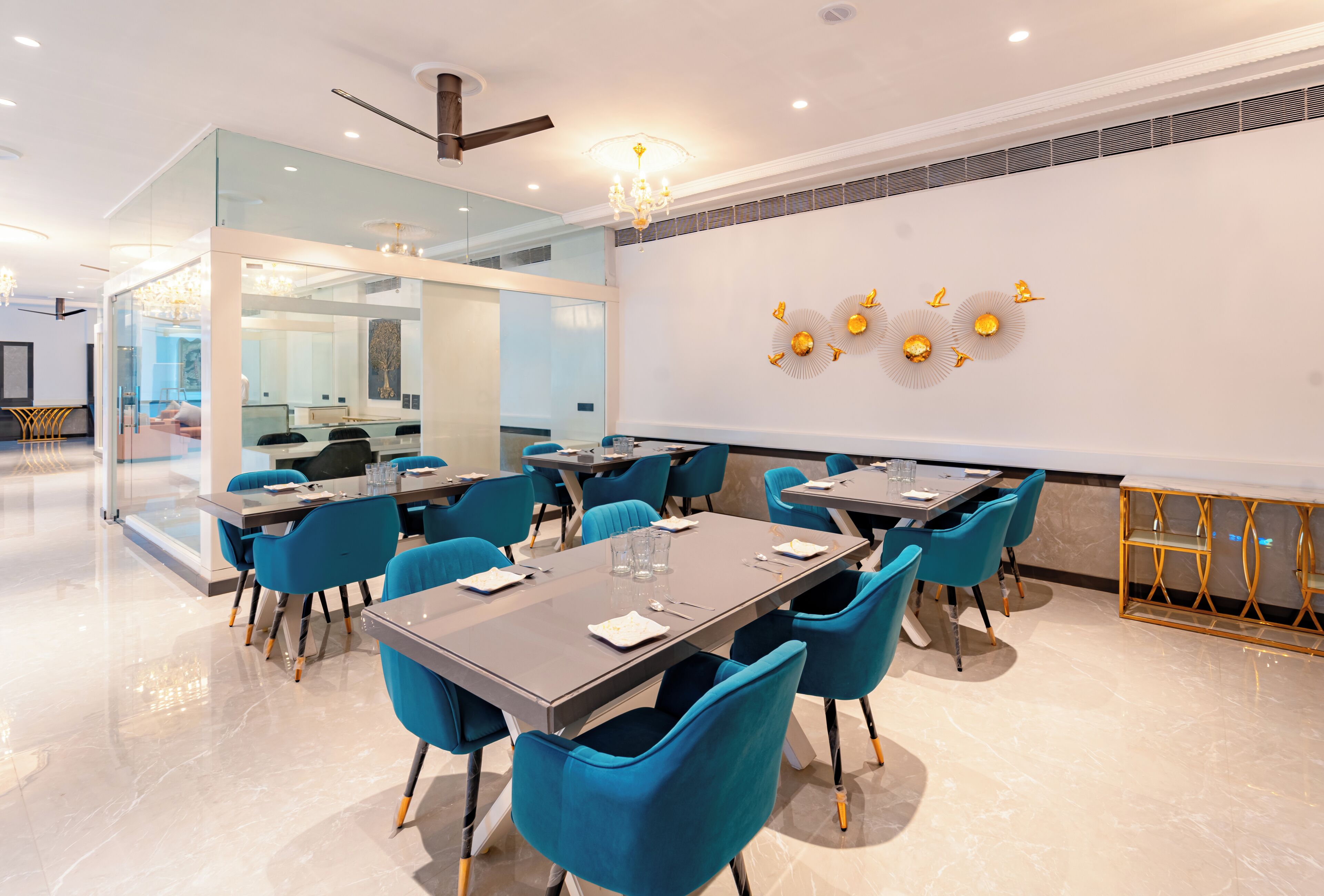 A modern conference room with glass walls, blue chairs, and a chandelier.