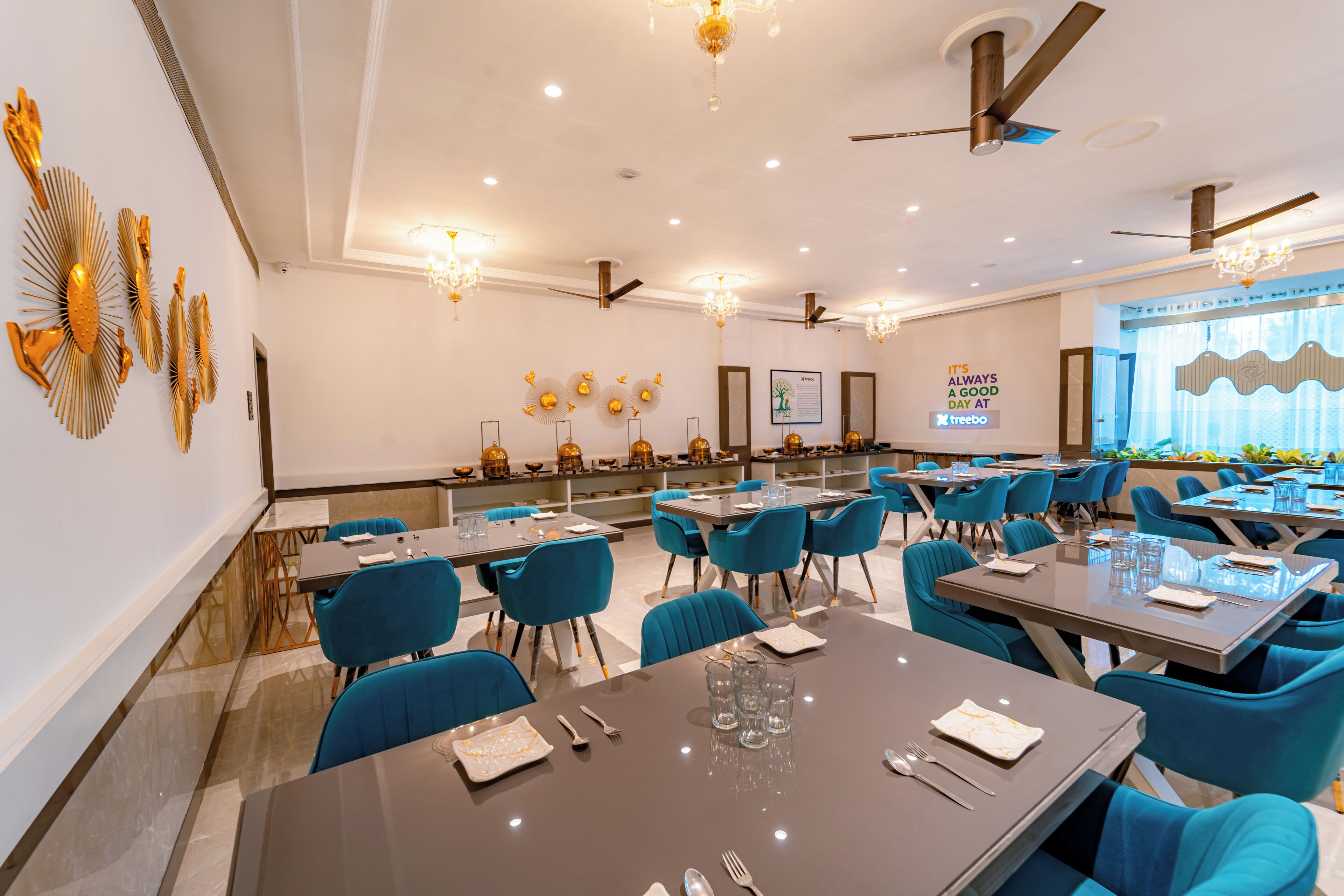 A modern dining area with blue chairs, tables set for meals, and decorative wall art.