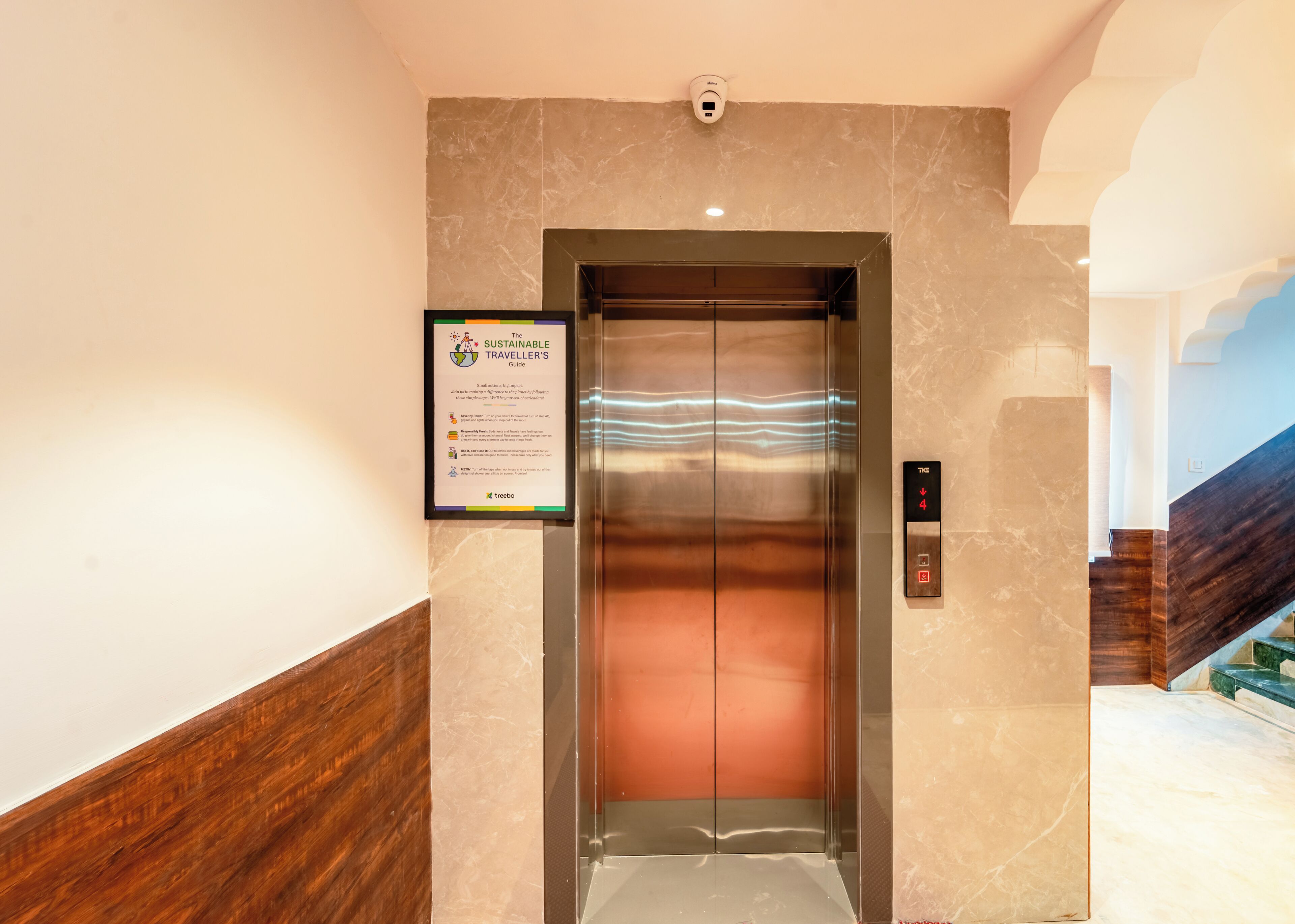 An elevator with a marble wall and a sign about sustainable travel.