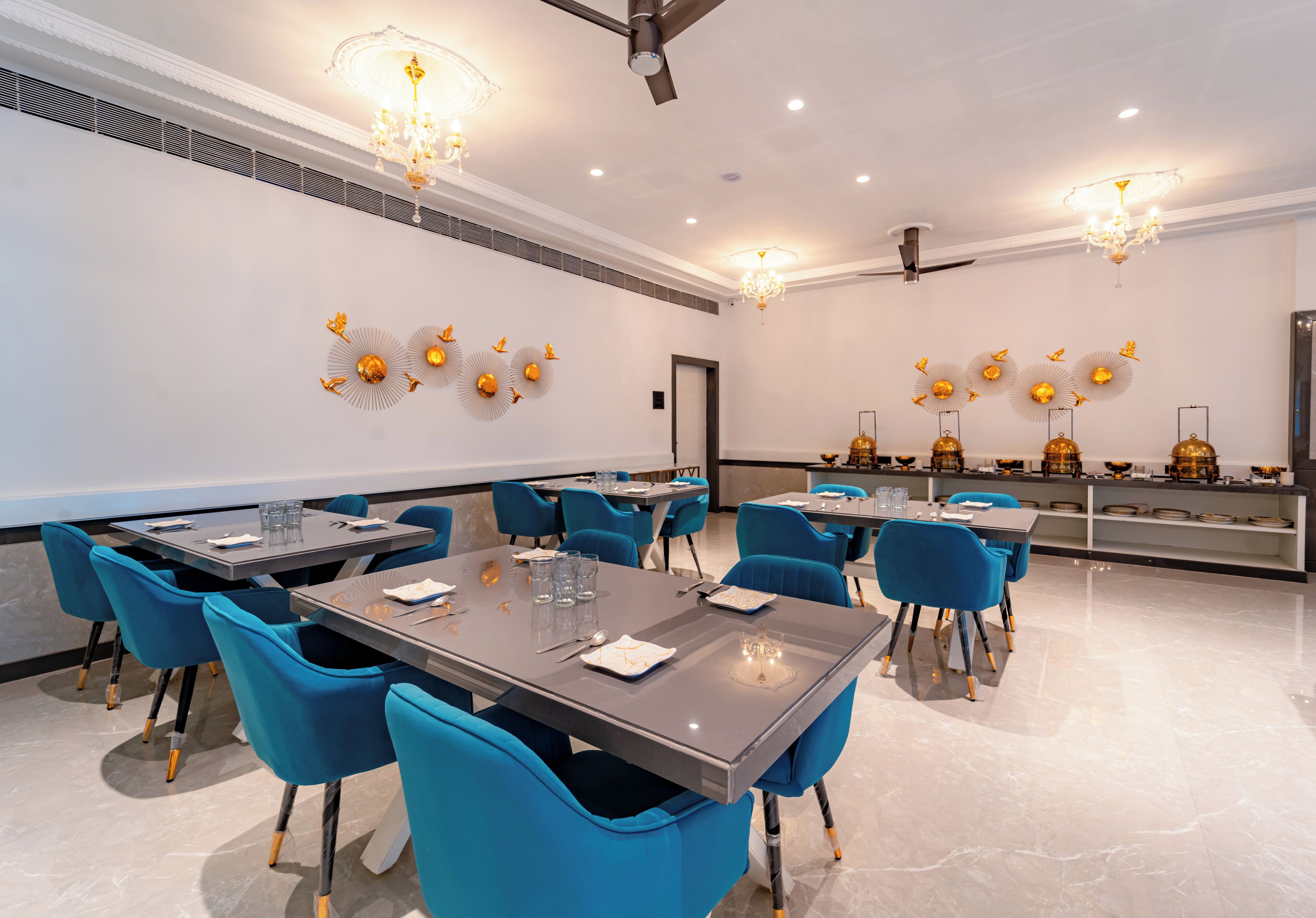 A modern conference room with blue chairs, grey tables, and decorative wall sconces.