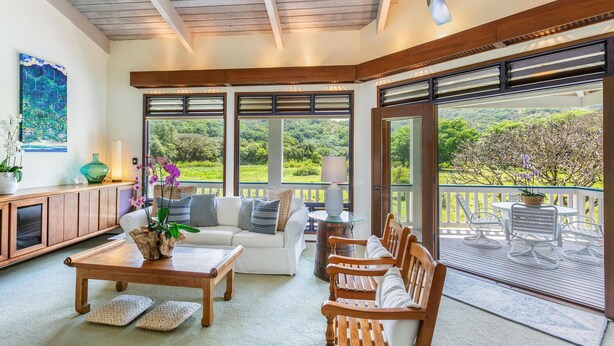 A sunlit room with a wooden ceiling, large windows, a sofa, a coffee table, and a view of greenery outside. - Kolohala in Haena is a tranquil place to enjoy your tropical vacation! (Haena)