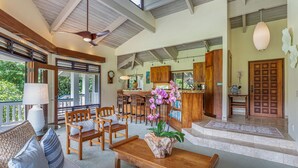 A spacious living area with a high ceiling, wooden furniture, and a view of the outdoors. - Kolohala in Haena is a tranquil place to enjoy your tropical vacation! (Haena)