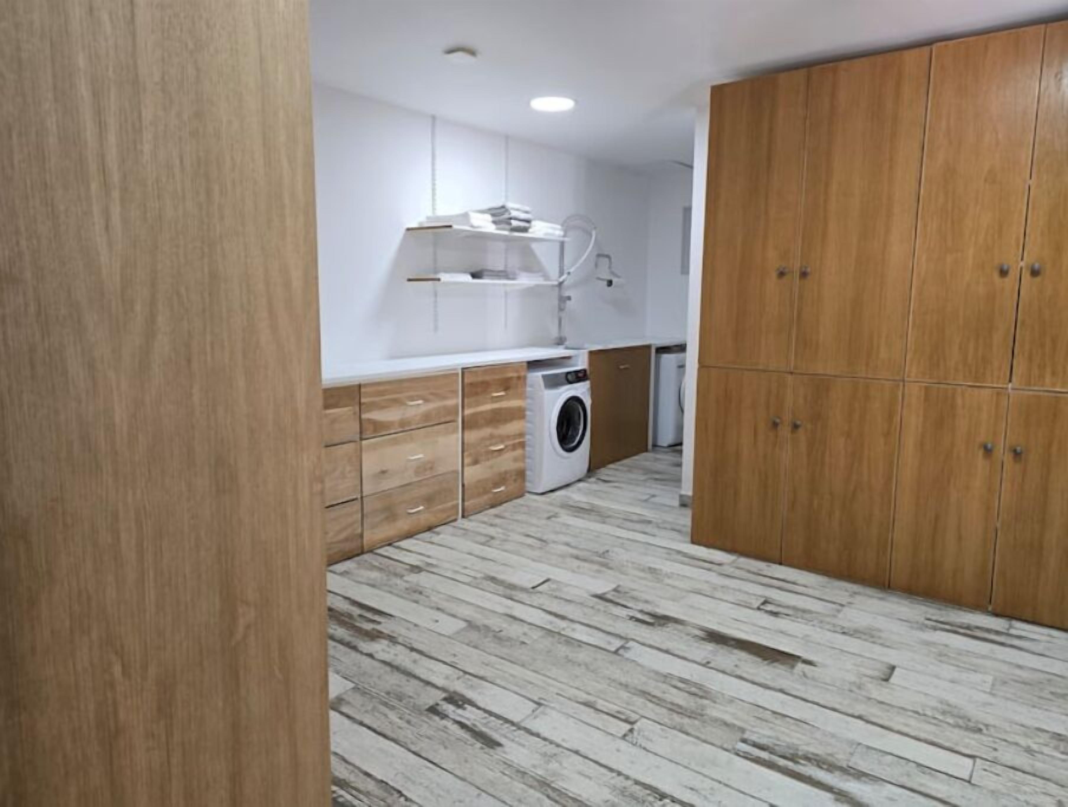 Eine kleine Küche mit Holzausstattung, einer Waschmaschine und einer Arbeitsplatte.