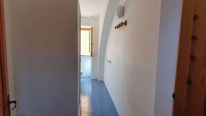 A narrow hallway with a wooden door on the left and a white wall with a small decorative item on the right.