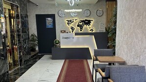 Un área de recepción con piso de mármol, alfombra roja, mostrador de recepción y un mapa del mundo en la pared.