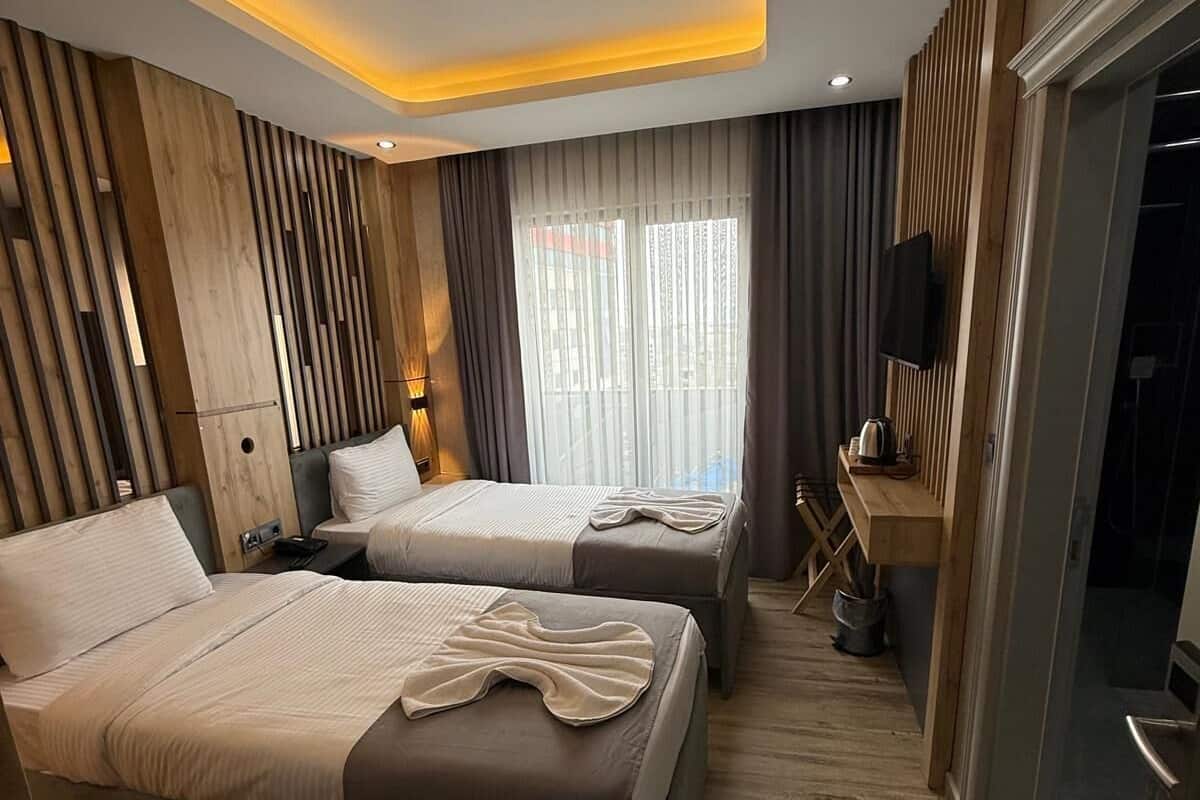 Moderni hotellihuone, jossa on kaksi sänkyä, työpöytä ja televisio.