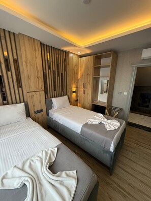 A modern hotel room with two beds, wooden paneling, a built-in wardrobe, and a seating area. - WORLD SAY HOTEL (Van)