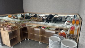 Montaje de bufé con diversos alimentos y bebidas, entre ellos frutas, verduras y refrescos.