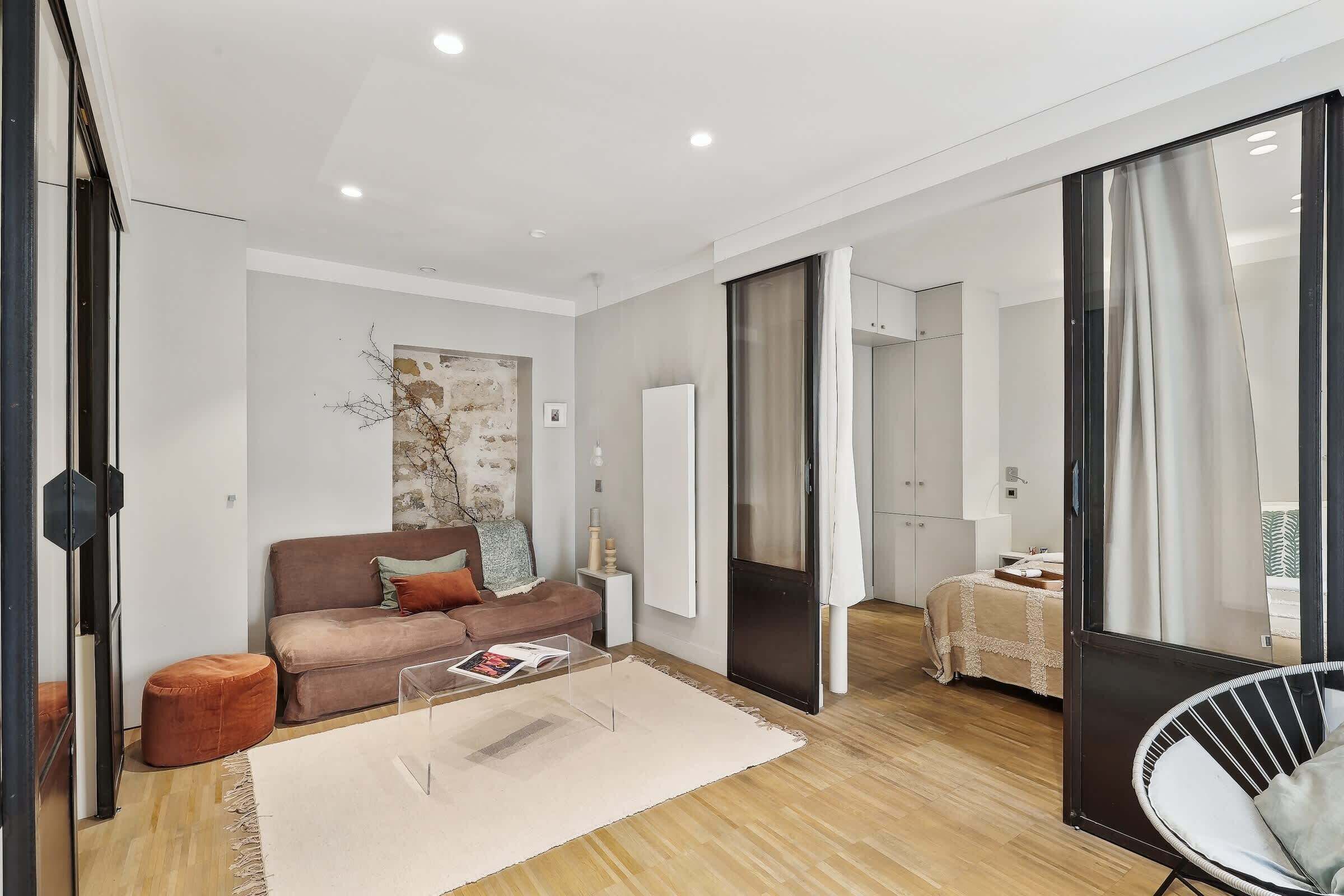 A modern living room with a sofa, ottoman, and a glass coffee table.