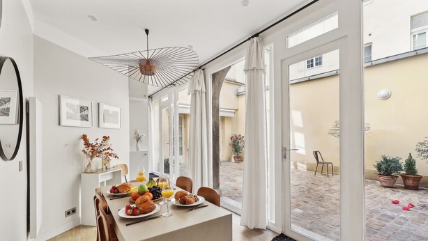 Un comedor con una mesa dispuesta para el desayuno, que incluye croissants, fruta y jugo.