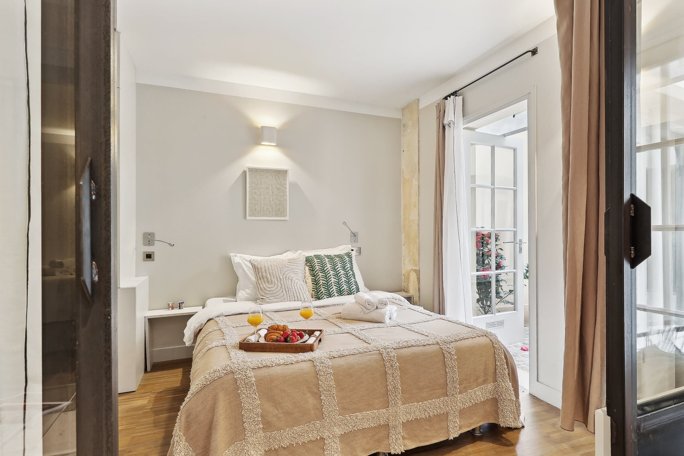 A bedroom with a bed, bedside table, and a tray of breakfast items.