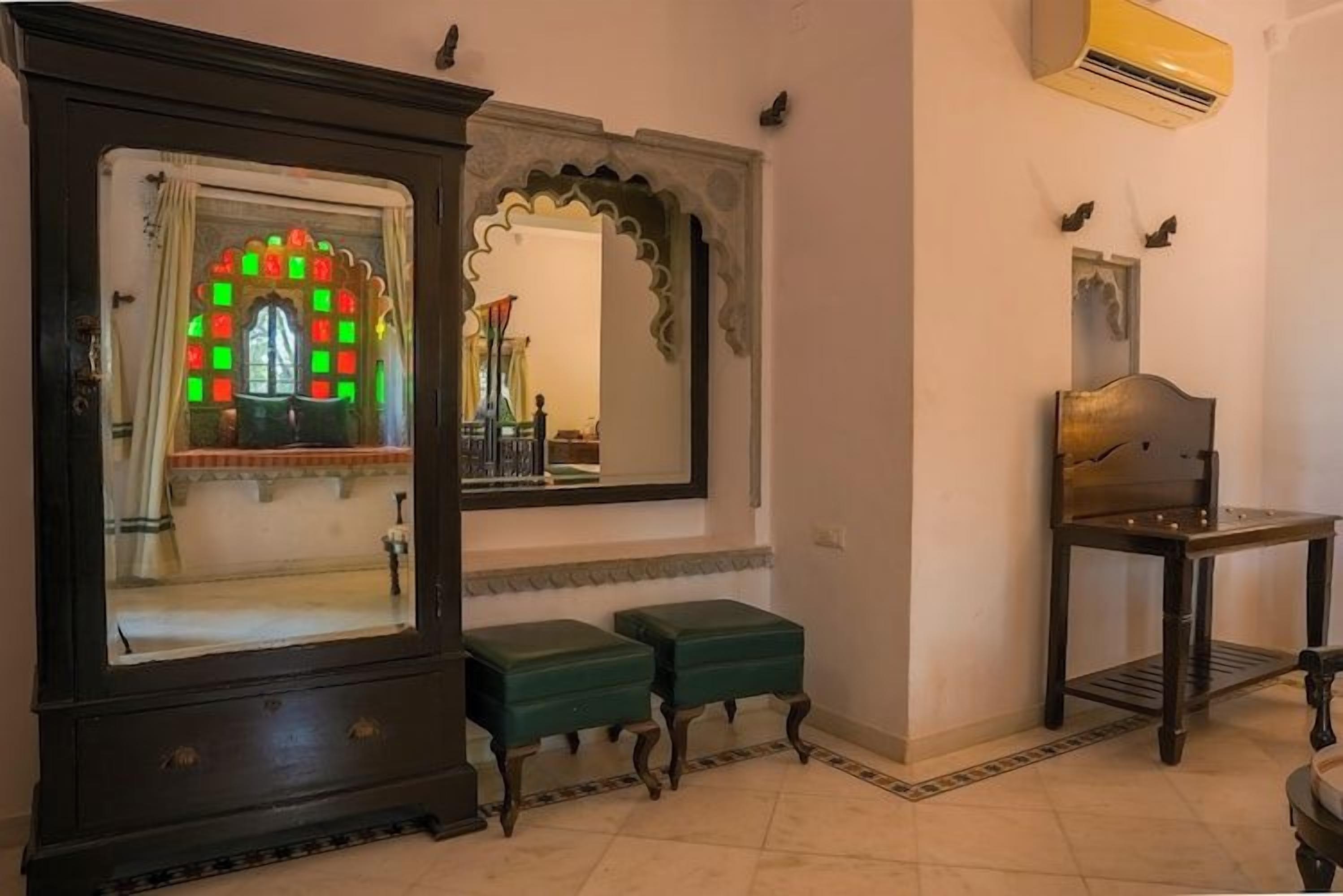 A room with a large wooden cabinet, a mirror with an ornate frame, and a small table.