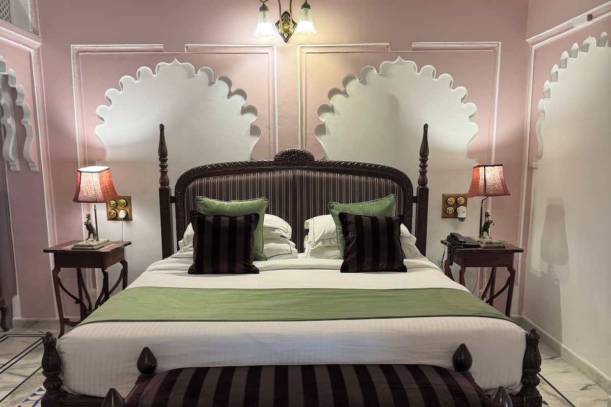 A bed with a wooden frame, two nightstands, and a chandelier.