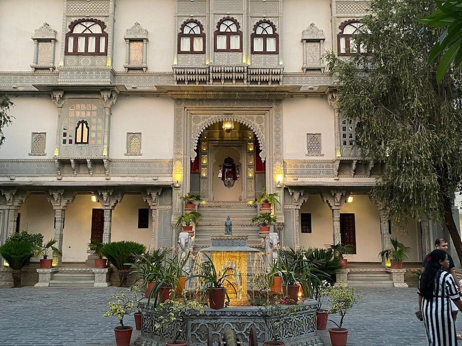A courtyard with a fountain, potted plants, and a statue.