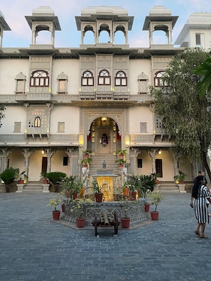 A courtyard with a fountain, potted plants, and a statue. - Hotel Amet Haveli (Udaipur)