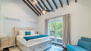 A bedroom with a bed, nightstands, a blue sofa, and a large window with curtains. - Casa De Moya & Mistico Beach Club + Boat Shuttle (San Pedro)