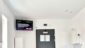Habitación de hotel con dos camas, televisión, puerta, lavabo y espejo.