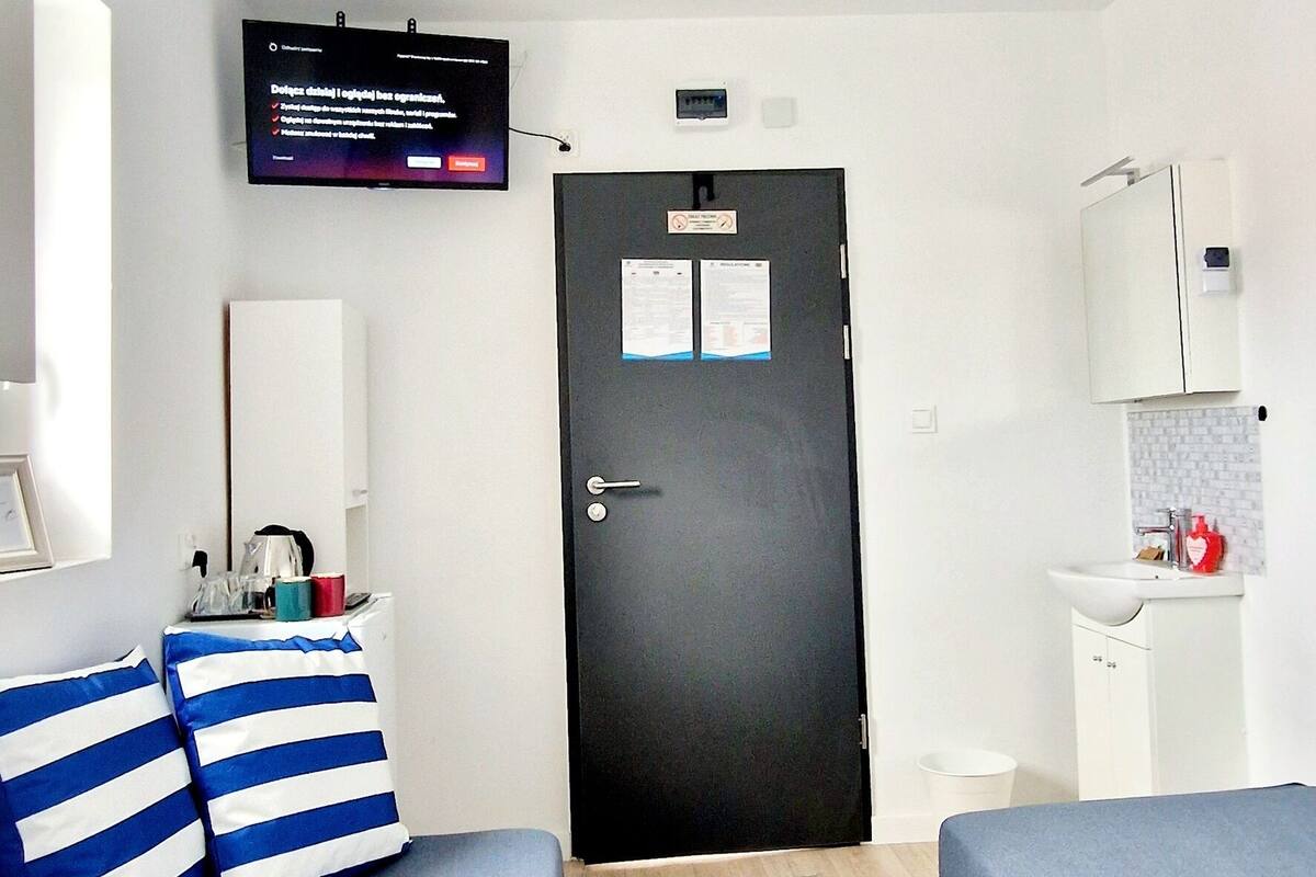 Ein Hotelzimmer mit zwei Betten, einem Fernseher, einer Tür, einem Waschbecken und einem Spiegel.