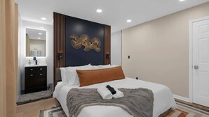 A modern hotel room with a large bed, a dark accent wall, a small bedside table, and a mirror. - Walk to OSU: Relaxing Retreat with Hot Tub (Columbus)