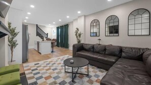 A modern living room with a brown leather sofa, a round coffee table, and a patterned rug. - Spacious 5-Bedroom Home with Hot Tub (Columbus)