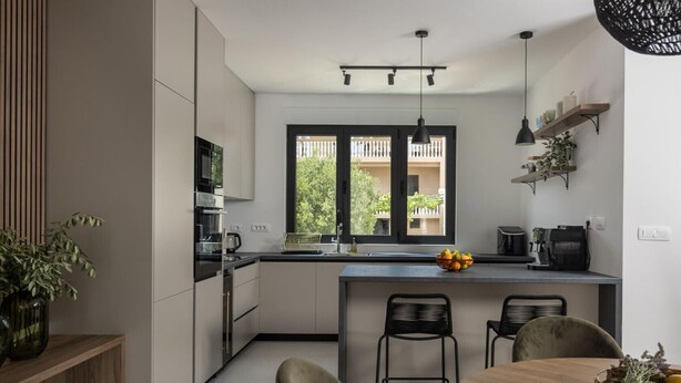 Una cocina moderna con una isla central, sillas negras y una mesa de comedor.