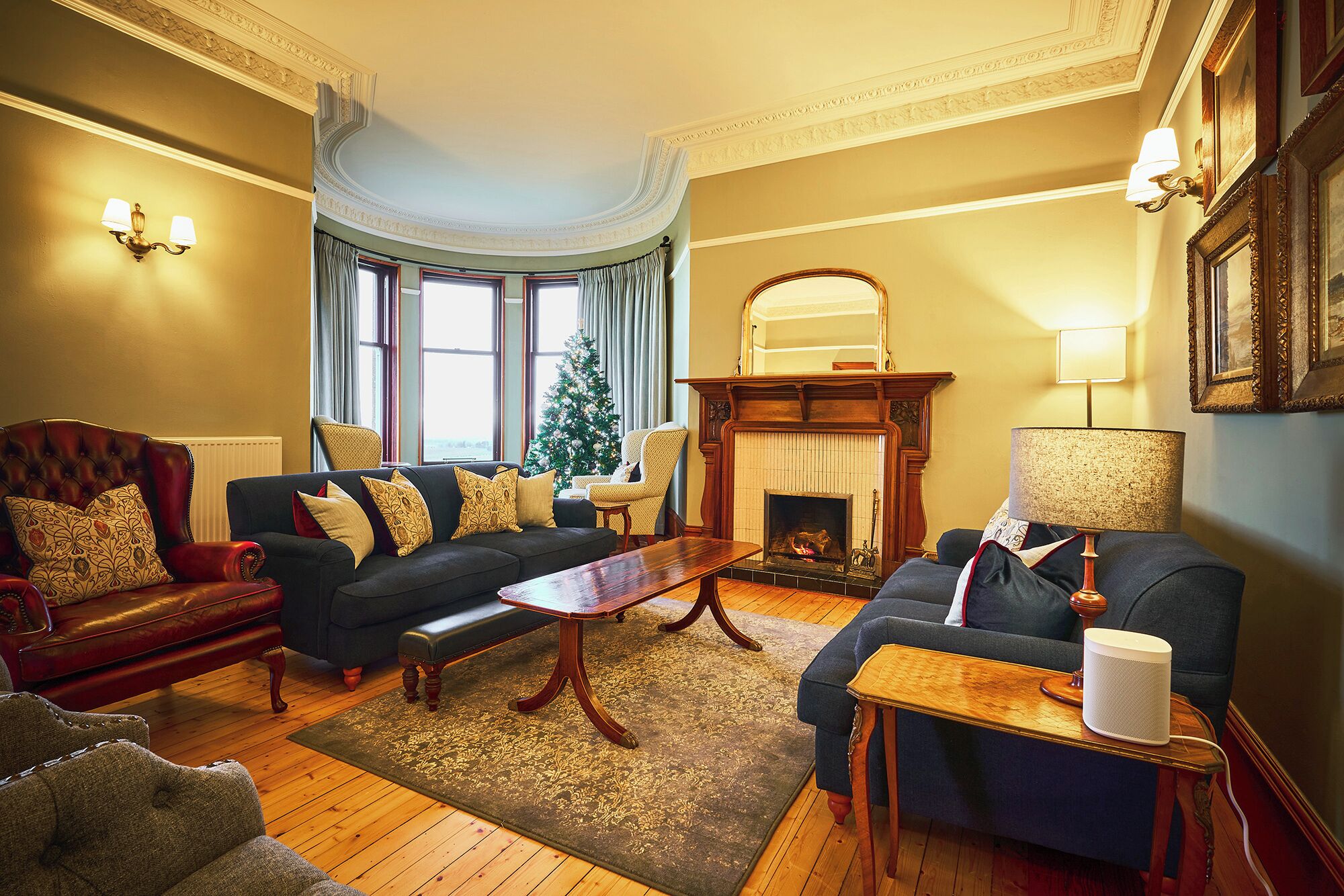 A traditional living room with a fireplace, two sofas, a coffee table, and a Christmas tree.
