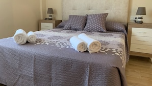A neatly made bed with a patterned bedspread and pillows, two bedside tables with lamps, and a wooden nightstand with a lamp.