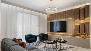 A modern living room with a sectional sofa, two armchairs, a coffee table, and a flat-screen TV mounted on the wall. - 4BR/3BA Townhome with private pool near Disney (Kissimmee)