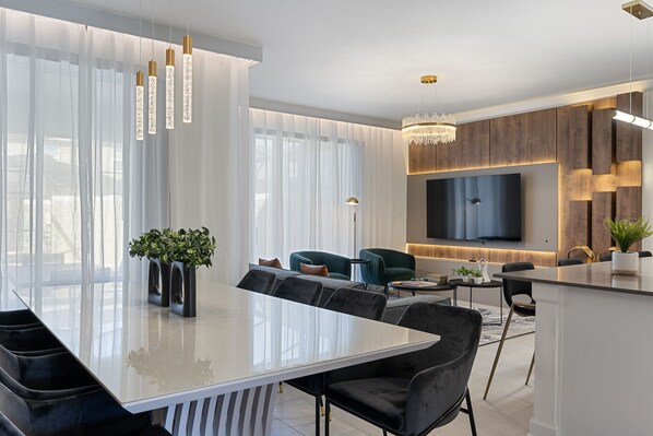 A modern dining area with a glass table, black chairs, and a chandelier.