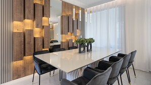 A modern dining area with a long table, black chairs, and a wooden accent wall. - 4BR/3BA Townhome with private pool near Disney (Kissimmee)