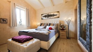 A bedroom with a bed, a bedside table, a mirror, and a wall with a painting. - Villa Jakob by Villas Guide (Kringa)