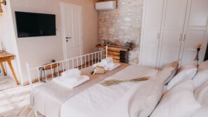 A bedroom with a bed, a TV, a stone wall, and a wardrobe.