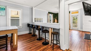 Een keuken met houten vloer, een bar met krukken en uitzicht op de omgeving via een deur.