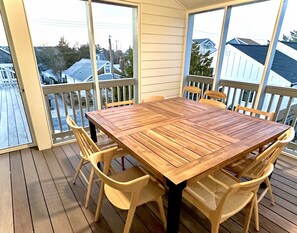 A wooden deck with a table and chairs, a sliding glass door, and a view of houses in the background. - 211 Midland Ave - New Construction close to Lewes Beach (Lewes)