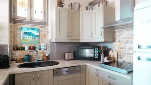 Una cocina con armarios blancos, lavavajillas, microondas y un lavabo.