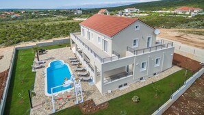 A modern two-story house with a swimming pool, a balcony, and a view of the surrounding landscape. - Villa Providenca with heated pool (Debeljak)