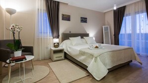 A modern bedroom with a large bed, a bedside table with a lamp, a chair, and a potted plant. - Villa Providenca with heated pool (Debeljak)