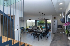Una cocina moderna con comedor, ventanas amplias y una escalera.