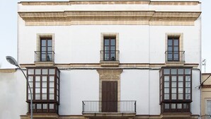 Un edificio de varios pisos con fachada simétrica, con ventanas y balcones con barandillas de metal distribuidos uniformemente.
