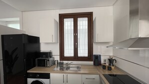 Cocina compacta con lavadora, tostadora, fregadero y estufa.