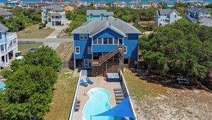A large blue house with a swimming pool, a hot tub, and a deck with lounge chairs. - Blue Bomber: Oceanside | Pool/Hot Tub | Dogs OK (Corolla)